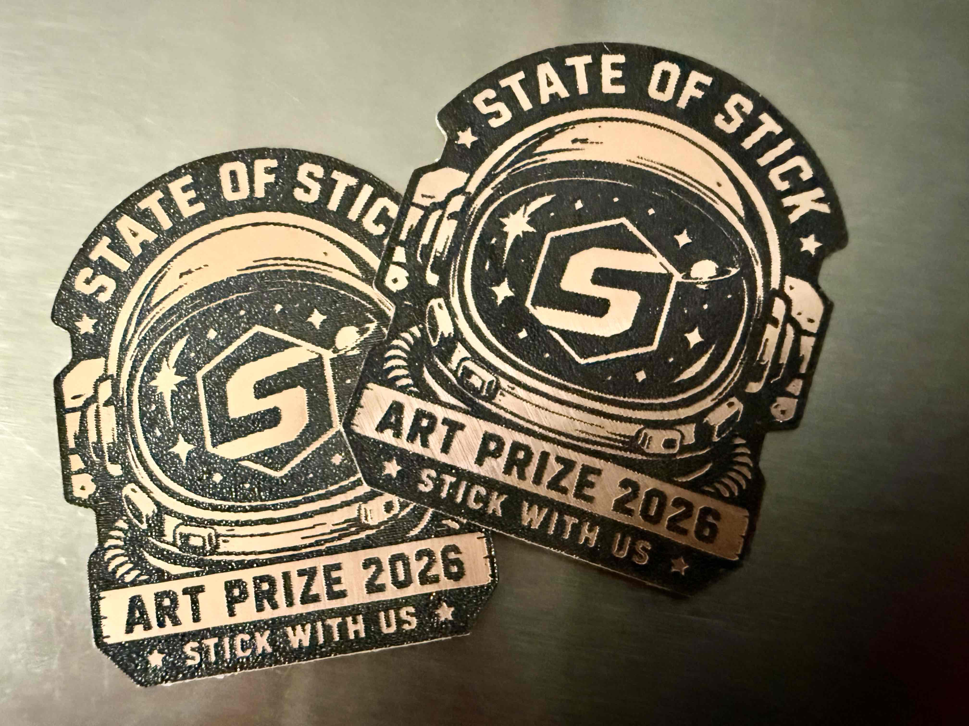 Two astronaut-helmet State of Stick ArtPrize emblems.