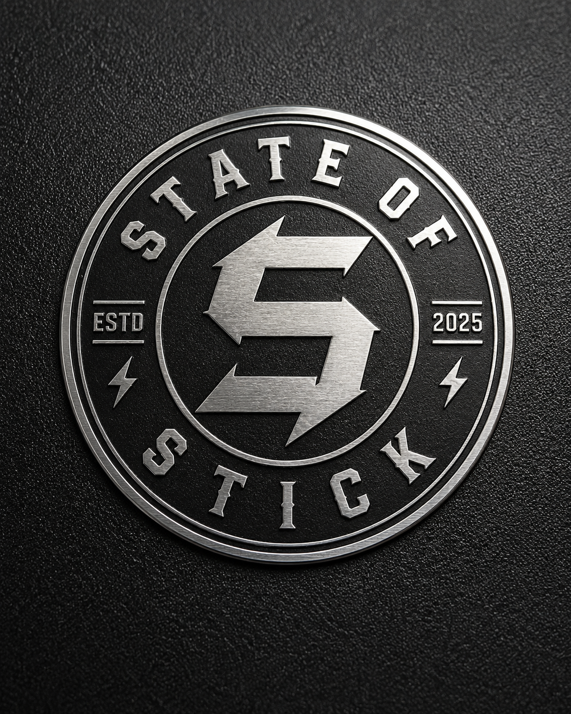 State of Stick metallic-finish composite emblem on black textured material