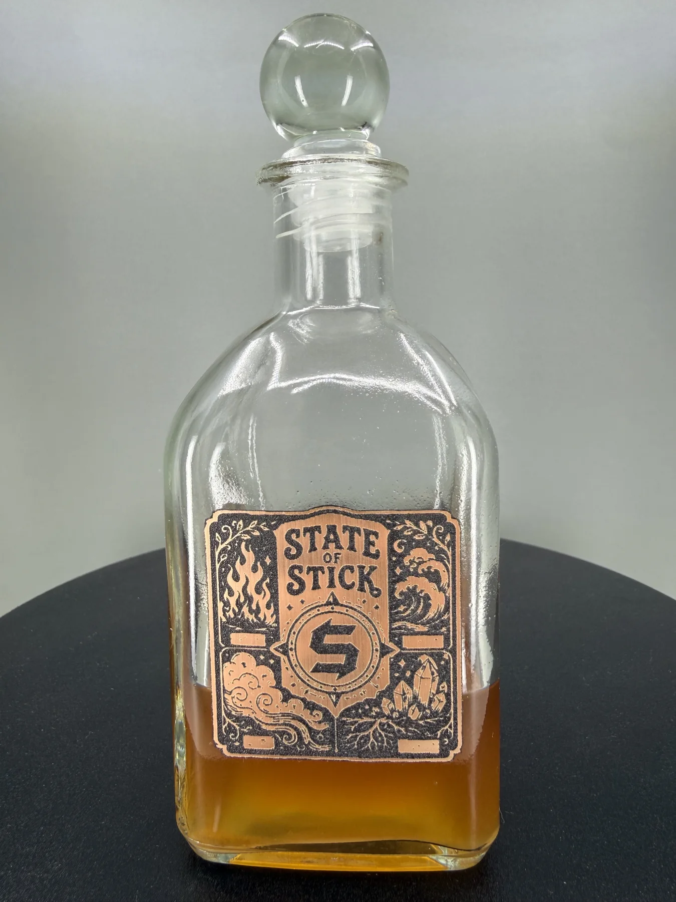 Custom Cauldron connected packaging case study featuring a glass bottle and dimensional State of Stick emblem
